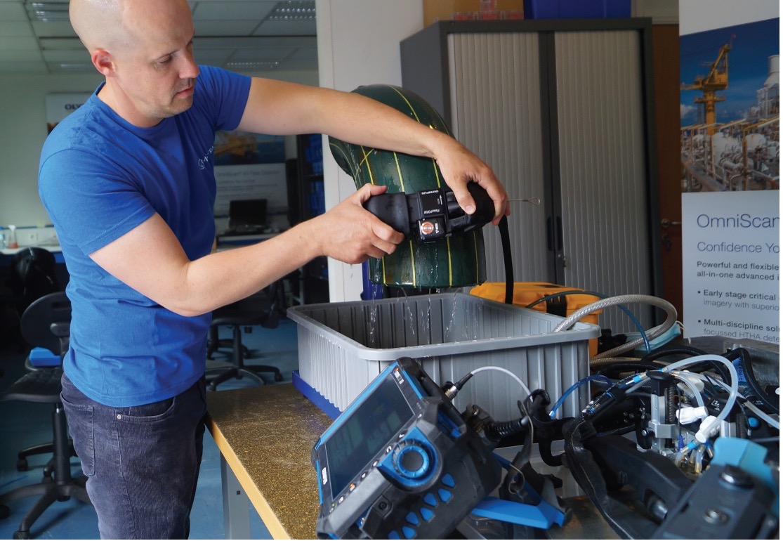 Mistras ISP工程师正在使用FlexoFORM扫查器和OmniScan X3相控阵仪器对管道弯头样品进行检测